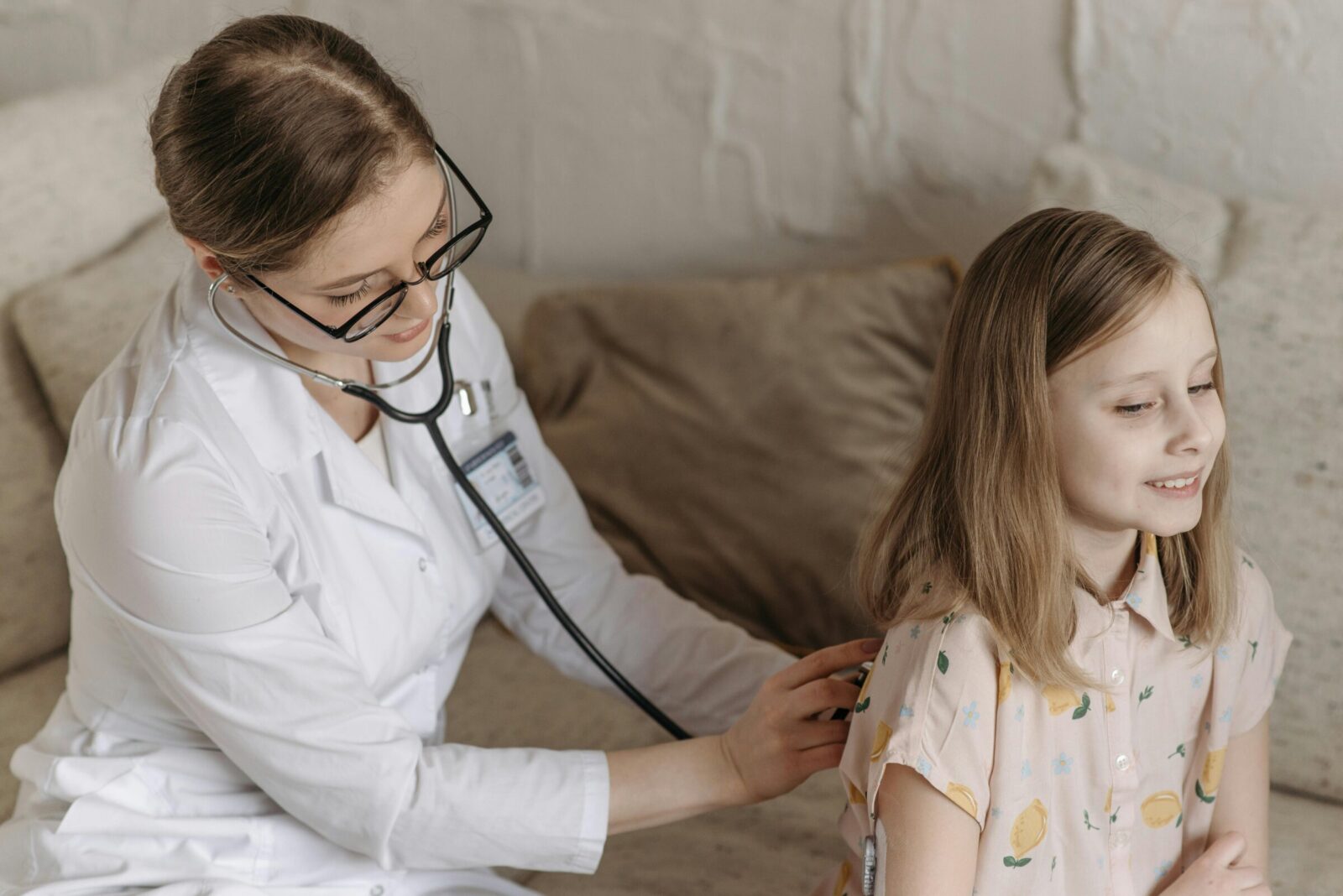 Pediatra a observar criança com estetoscópio em consulta de Pediatria